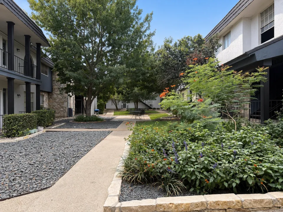 Flower-lined courtyard walkway between buildings at Wilshire Woods